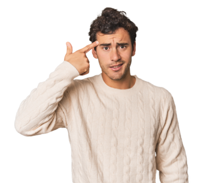 Young Hispanic man in studio showing a disappointment gesture with forefinger.