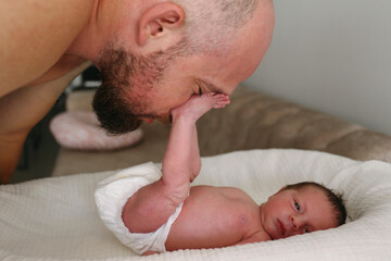 Father embracing cute baby daughter lying in crib at home