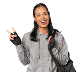 Young Filipina athlete with gym backpack joyful and carefree showing a peace symbol with fingers.