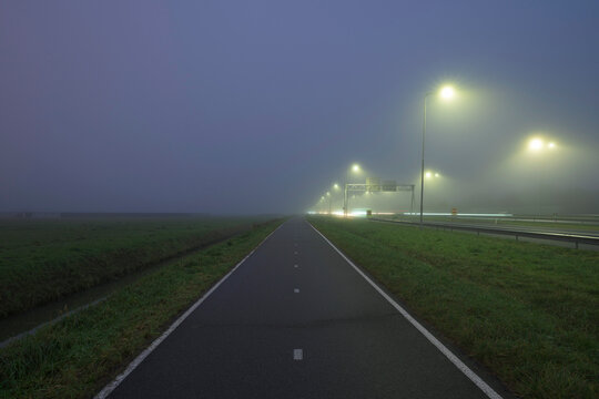 Highway with lights under foggy sky at night