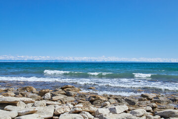 Issyk-Kul lake, stone coast. Summer natural landscape, vacation in Kyrgyzstan. Clear blue sky,...