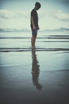 Teenage boy standing ankle deep in water on the beach, Koh Yao, Phang Nga, Thailand