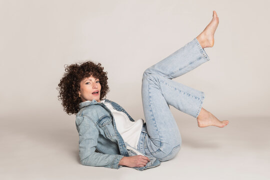 Beautiful woman in denim clothes lying down on white backdrop