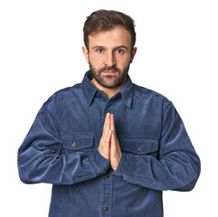 Studio portrait of young Hispanic male praying, showing devotion, religious person looking for...