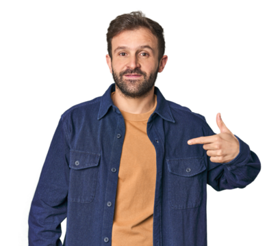 Studio portrait of young Hispanic male person pointing by hand to a shirt copy space, proud and confident