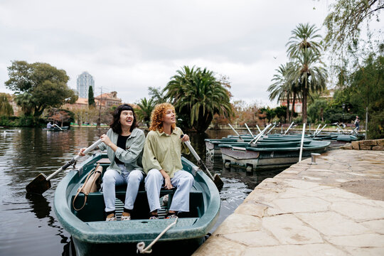 Happy lesbian couple riding rowboat in lake at Ciutadella Park, Barcelona, Spain