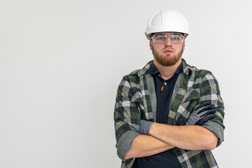Portrait of a male builder. Engineer in overalls and helmet on a light background.