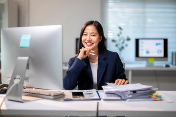 A woman is sitting at a desk with a computer monitor in front of her