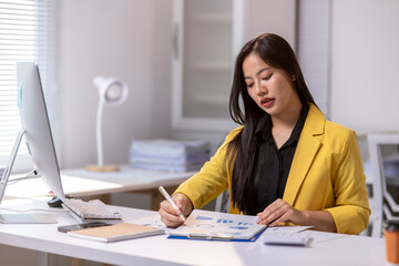 A woman is sitting at a desk with a computer monitor and a yellow jacket