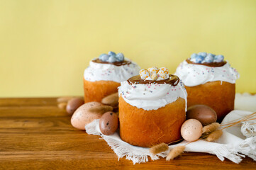 Easter cakes with white icing and small eggs on a vibrant yellow background, perfect for holiday themes and baking