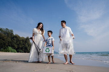 Happy Family of volunteers worker cleaning plastic bottle on the beach with trash bags.