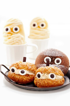Close-up of Halloween ghost cream filled chocolate bread and cream puffs with googly eyes