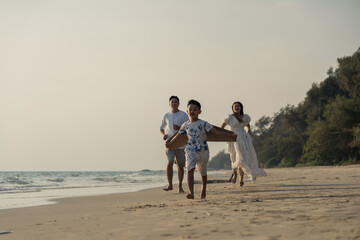 Happy asian family enjoy together on the beach in holiday vacation. Silhouette of the family holding hands enjoying the sunset on the sea beach. Happy family travel, trip  family holidays weekend.