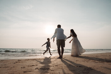 Happy asian family enjoy together on the beach in holiday vacation. Silhouette of the family holding hands enjoying the sunset on the sea beach. Happy family travel, trip  family holidays weekend.
