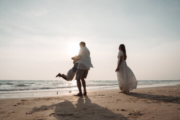 Happy asian family enjoy together on the beach in holiday vacation. Silhouette of the family holding hands enjoying the sunset on the sea beach. Happy family travel, trip  family holidays weekend.