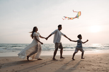 Happy asian family enjoy the sea beach together. father, mother and son having fun playing kite on...