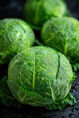 Fototapeta premium Close-up of fresh green cabbages with water droplets on dark background