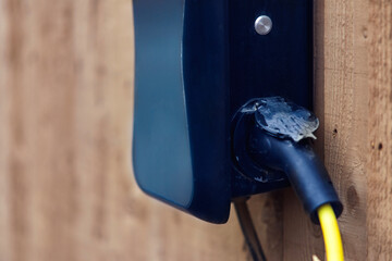 Electrical connection point mounted on a wooden wall with visible wiring in late afternoon light