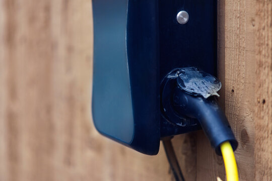 Electrical connection point mounted on a wooden wall with visible wiring in late afternoon light