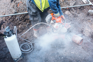 Construction worker operates a power petrol cutter at a construction site during the day