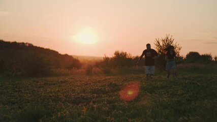 Beautiful couple playing with pinscher dog at sunset.Beautiful sunny landscapes around them.Family playing with dog.