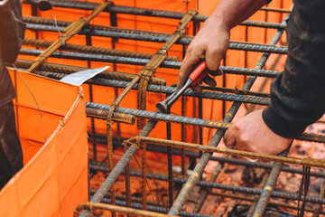 Close-up of Steel fixer assembling steel rebar framework on a construction site creating support structures for a concrete foundation