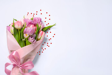 Bouquet of beautiful tulips and red paper hearts on white background
