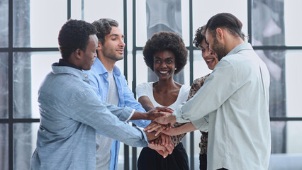 a group of successful business diverse people in the office stands embracing