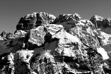 This black and white photograph showcases the majestic peaks of the Dolomites, a UNESCO World Heritage site in northern Italy. The image captures the rugged and imposing rock covered with snow