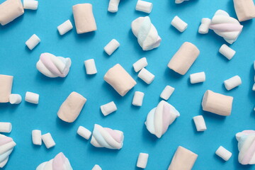 Texture of different marshmallows lying on a blue background.