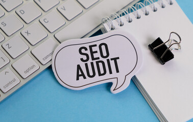 A white keyboard with a clip on it and a white paper with the word SEO Audit written.