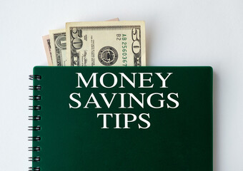 A green spiral notebook with money savings tips written on it