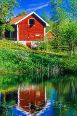 Red cottage on the shore of a lake © Lars Johansson