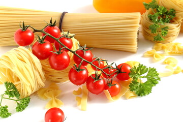 On a white background lie long straight spaghetti and pasta in the form of baskets with vegetables.
