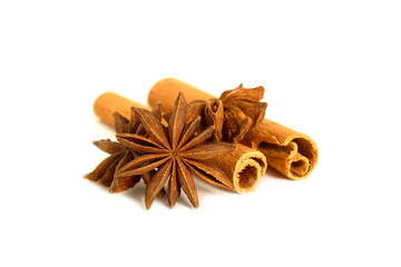 On a white background lie the cinnamon spice, two sticks and an anise flower.	