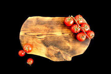On a black background on a cutting board lie ripe red tomatoes with space for text.