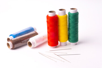 Colorful sewing thread set and needles isolated on background.
