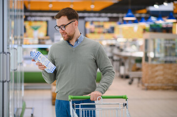 A handsome man buys milk in a supermarket