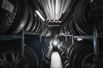 New tires in the tire rack in the car repair shop. Tire at repairing service garage background. Replacing winter and summer tyre for safety road trip.