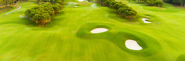 A panoramic view of a golf course with sand traps and lush greenery