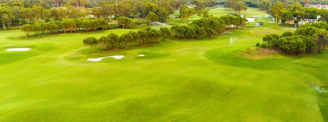 An aerial view of a spacious golf course with sand traps and open greenery.