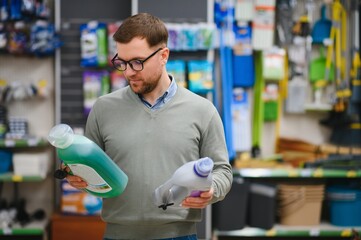 Young man in the supermarket in the household chemicals department. Large selection of products. A...