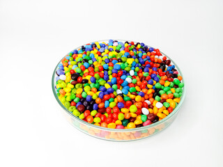 Rainbow masterbatch plastic granules, polymer carries pigment in a glass cup poured with a white...