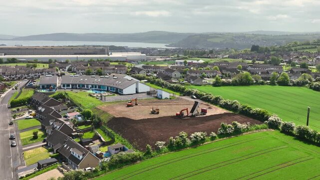 Slow motion aerial view of machinery at construction of sports fields Corran Integrated Primary School Larne N. Ireland 10-02-20 