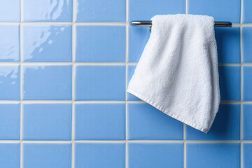 White Towel Hanging on a Chrome Bar Against Blue Bathroom Tiles