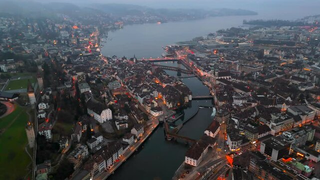 Stadtbild von Luzern Luftaufnahme, Schweiz bei Nacht mit Stadtlichtern, nebligem Wetter. Luftbild vom Fluss Reuss und allen bekannten Bruecken am Abend. Aerial view of city center of Lucerne at night