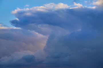 Sun rays illuminate gray-blue clouds, giving them volume and a play of light and shadow. A natural landscape conveying the dynamics and grandeur of the vast sky.