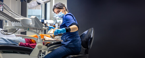 Fototapeta premium Young female dentist treating teeth of a girl in a dental office. Dentistry concept.