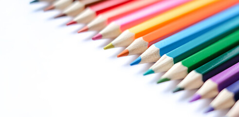A row of colored pencils are lined up on a white background. 