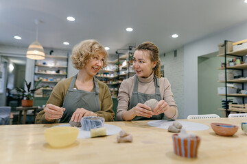 Mother and daughter engage in an art workshop, strengthening their bond through handcraft. Two generations of women take part in a pottery lesson, sharing knowledge and creativity.